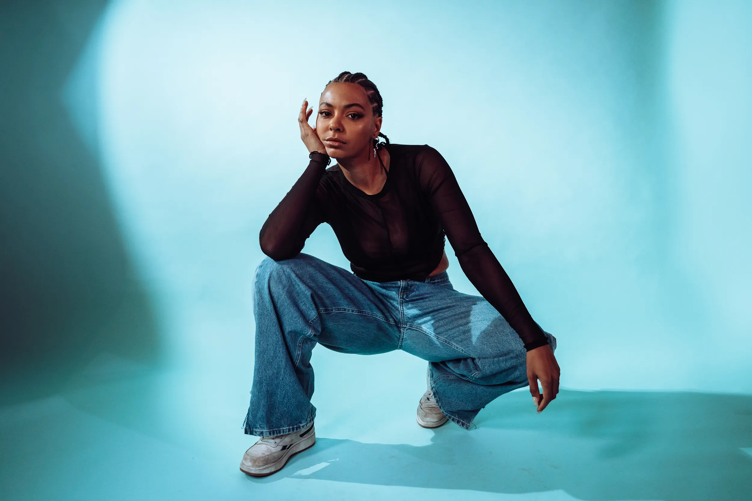 Eine hockende Person vor blauem Hintergrund.