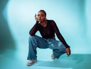 Eine hockende Person vor blauem Hintergrund.