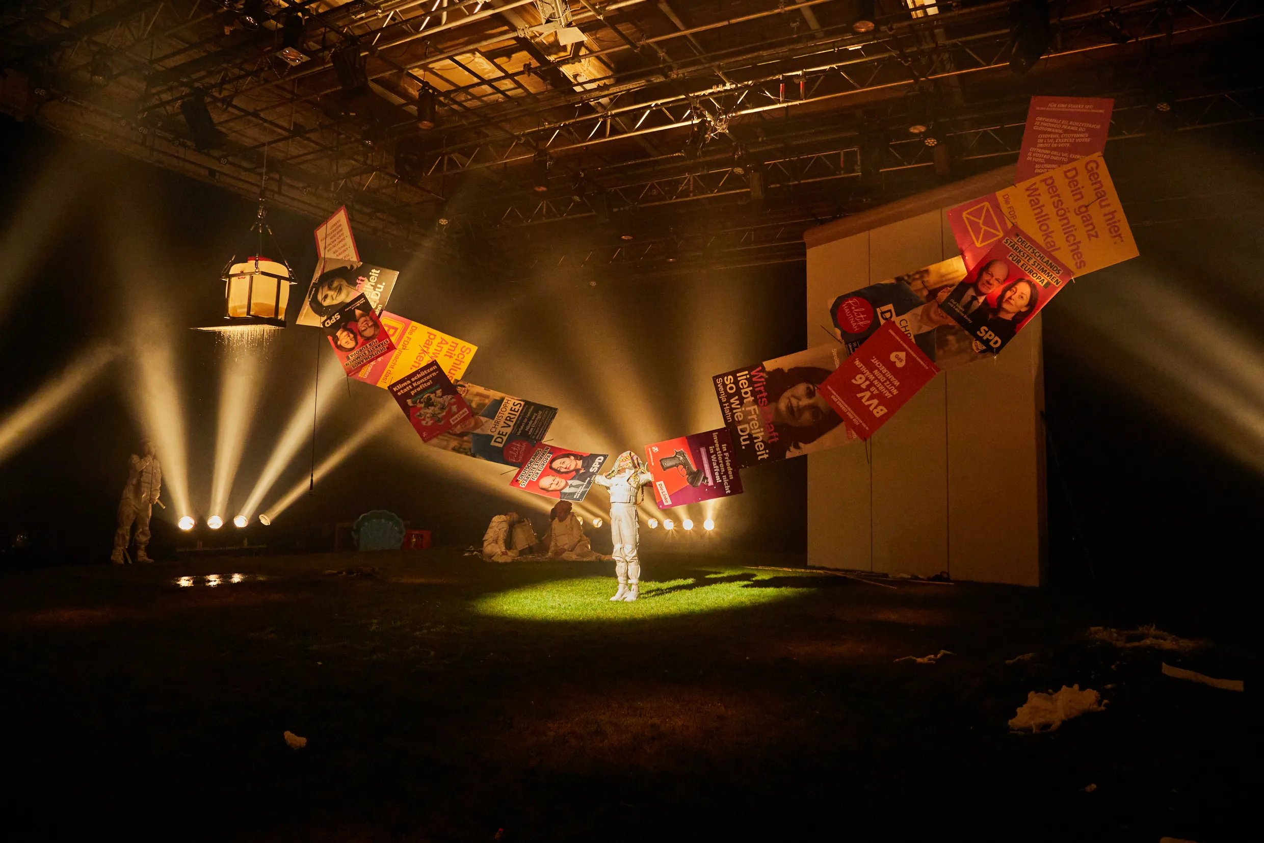 Eine Person streckt beide Arme zur Seite aus, die von aneinanderklebenden Wahlplakaten verlängert werden.