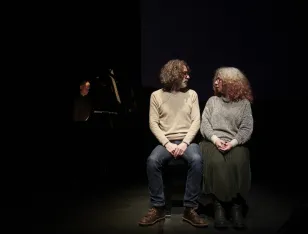 Zwei Personen sitzen nebeneinander und schauen sich an.