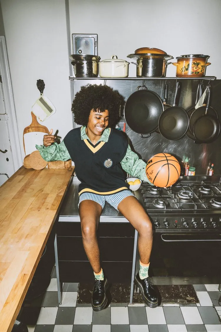 Eine Person sitzt auf einer Küchenplatte und hält einen Basketball in der Hand.