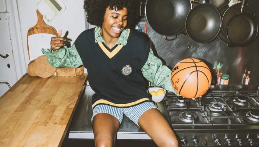 Eine Person sitzt auf einer Küchenplatte und hält einen Basketball in der Hand.