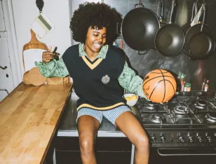 Eine Person sitzt auf einer Küchenplatte und hält einen Basketball in der Hand.