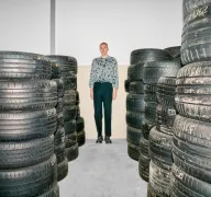 Eine Person steht zwischen Stapeln von Autoreifen.
