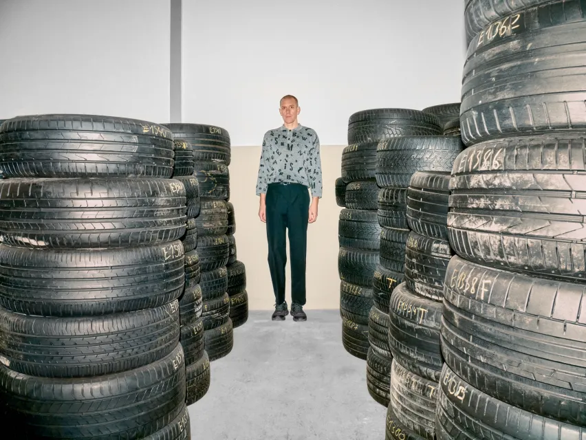 Eine Person steht zwischen Stapeln von Autoreifen.