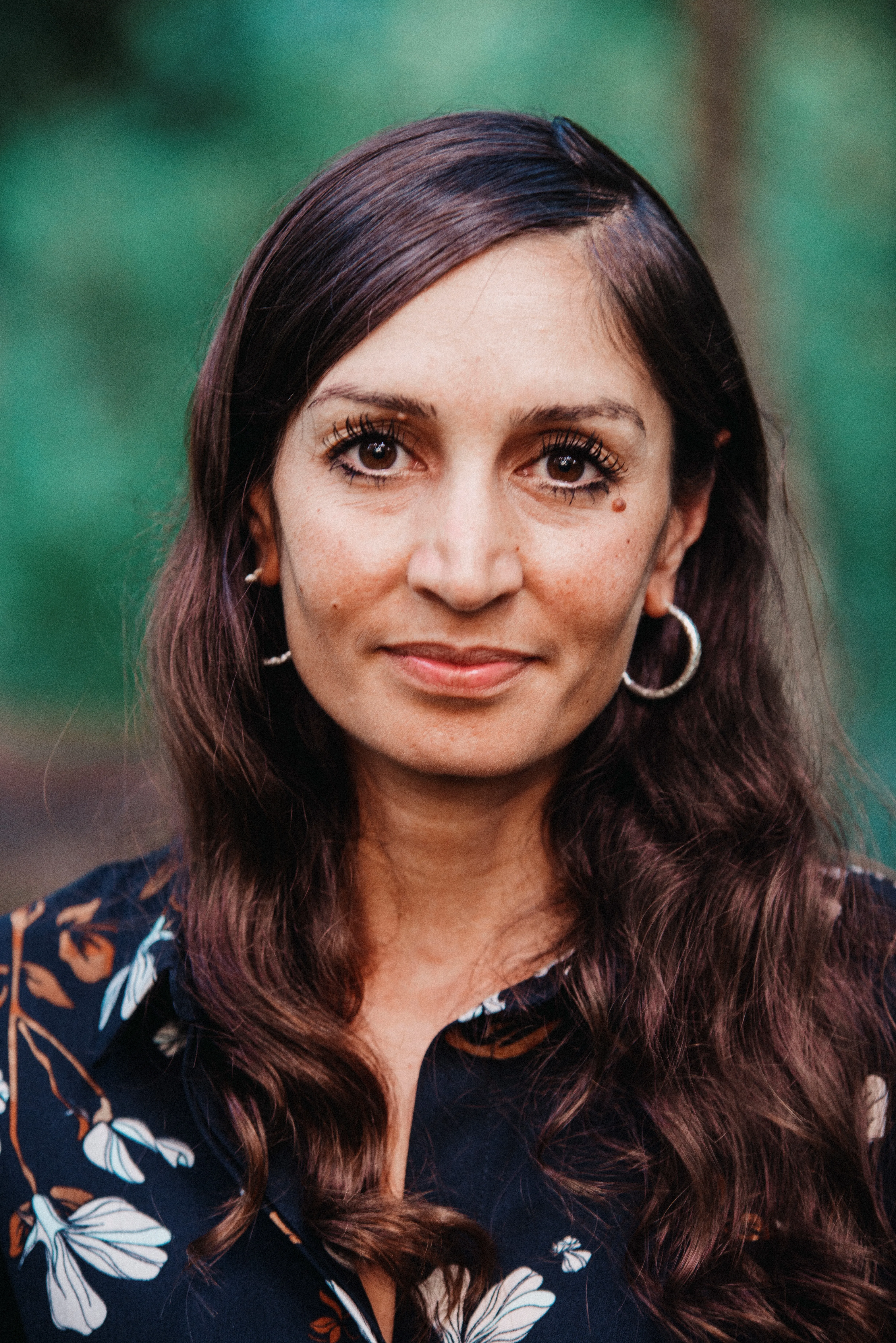 Porträt einer lächelnden Frau mit langen braunen Haaren.