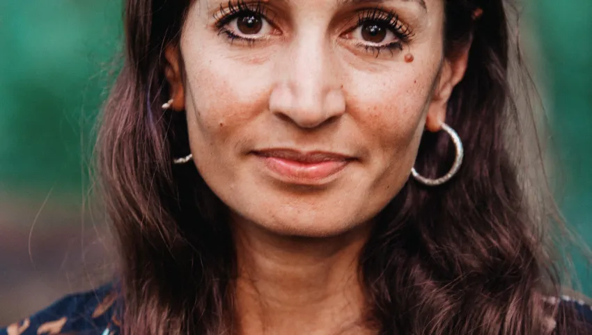 Porträt einer lächelnden Frau mit langen braunen Haaren.