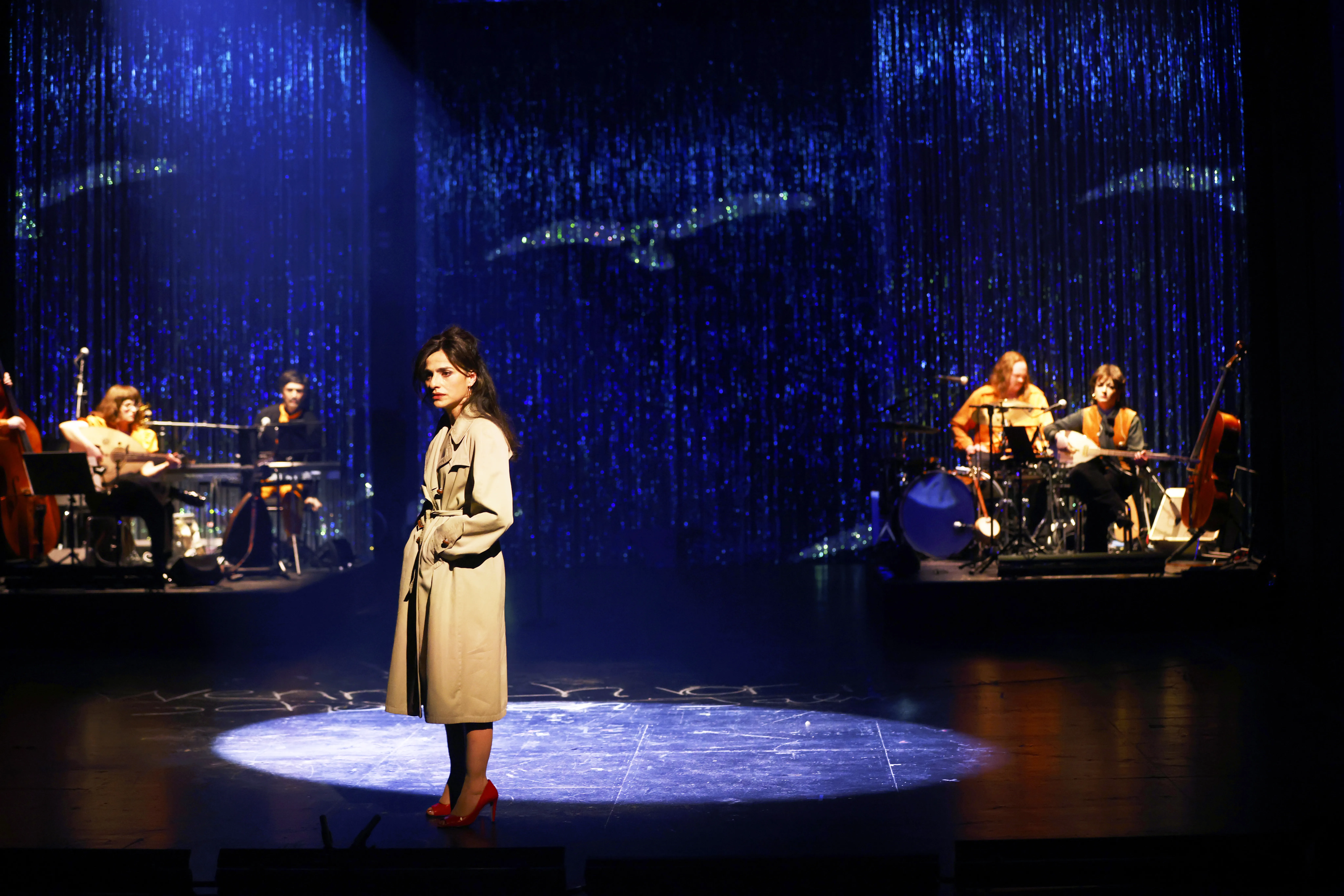 Eine Frau im beigen Mantel steht im Licht.