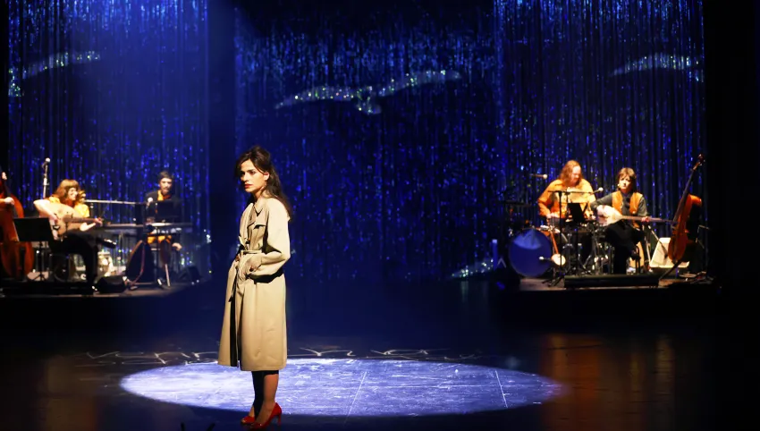 Eine Frau im beigen Mantel steht im Licht.