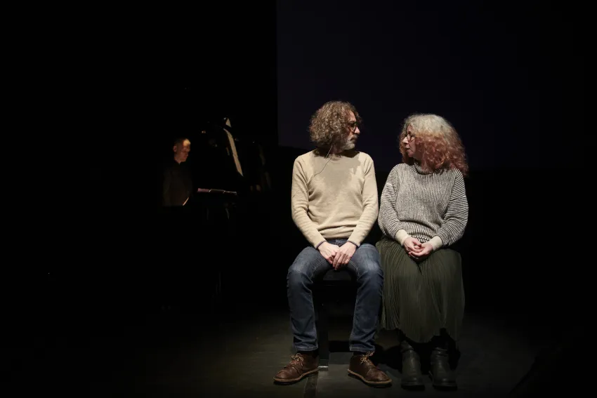 Zwei Personen sitzen nebeneinander und schauen sich an.