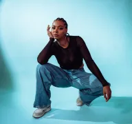 Eine hockende Person vor blauem Hintergrund.