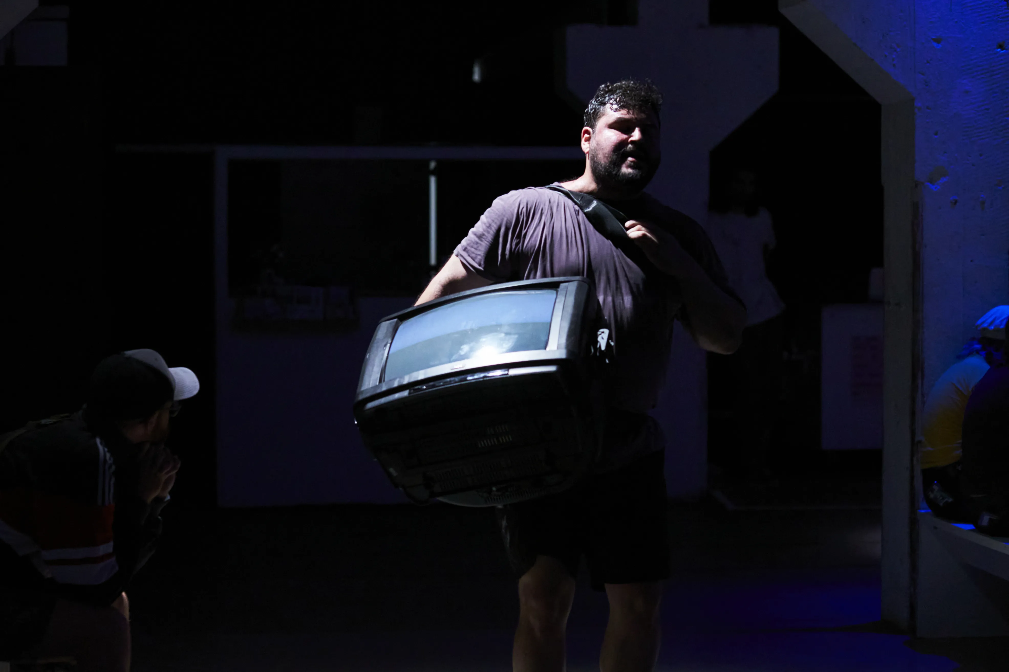 Eine Person, die sich in einem dunklen Raum befindet und einen Fernseher trägt.