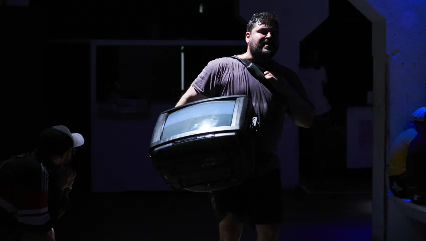 Eine Person, die sich in einem dunklen Raum befindet und einen Fernseher trägt.