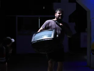 Eine Person, die sich in einem dunklen Raum befindet und einen Fernseher trägt.