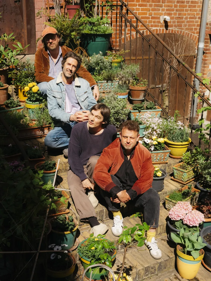 Vier Personen sitzen hintereinander auf einer Treppe, umgeben von Pflanzen.