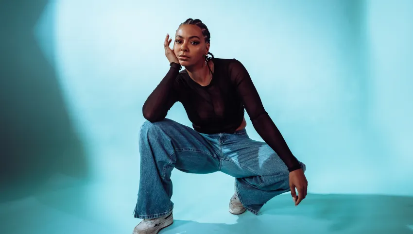 Eine hockende Person vor blauem Hintergrund.