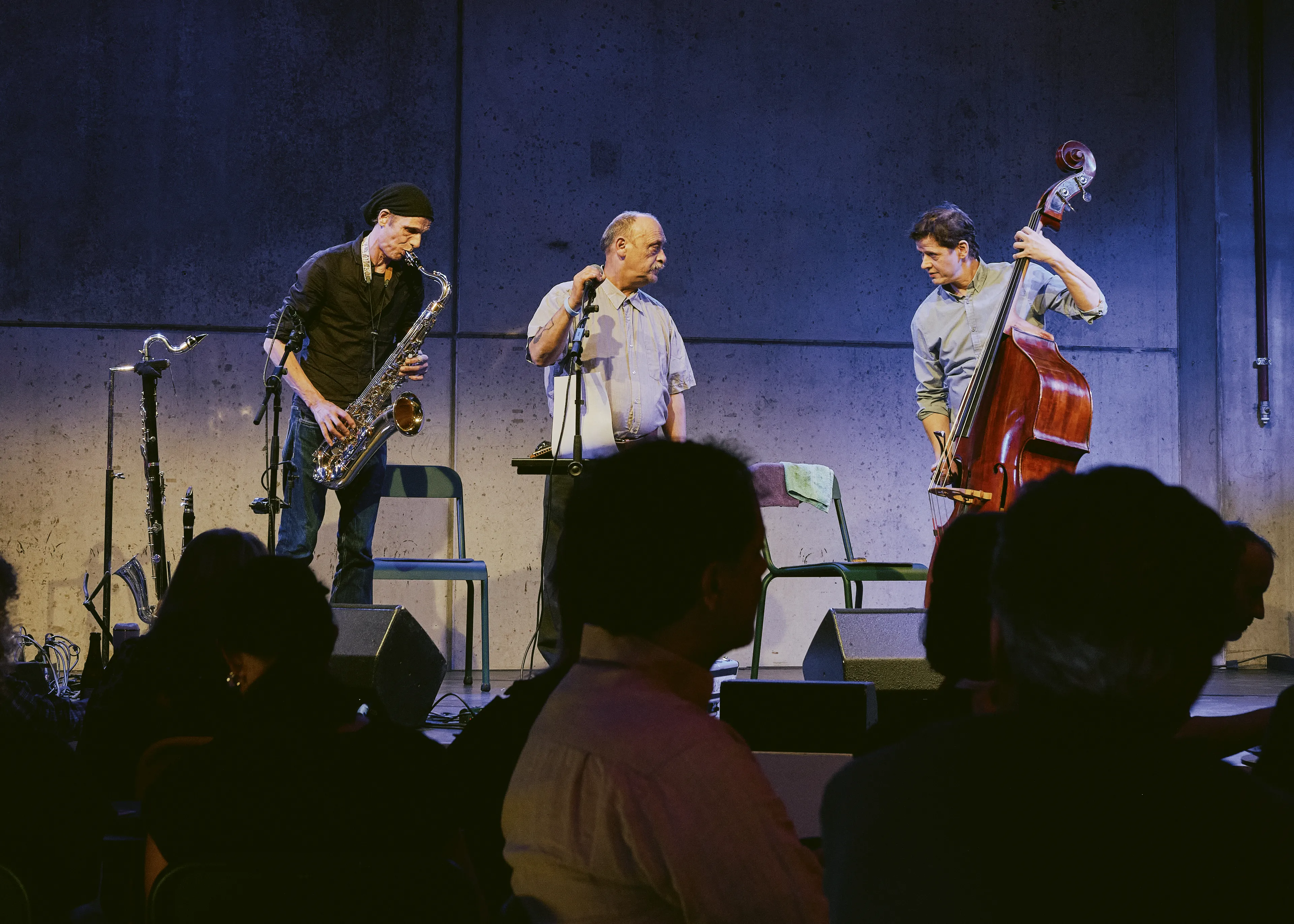 Momentaufnahme des Auftritts von O'Chavo Pretzlie bei der Brechtnacht. Ein Saxophonist, ein Sänger, ein Kontrabassist
