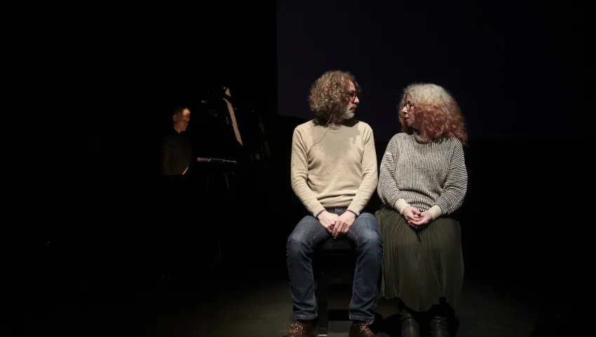 Zwei Personen sitzen nebeneinander und schauen sich an.