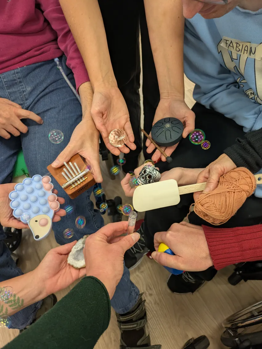 Ein Kreis von Händen, die unterschiedliche Gegenstände halten.