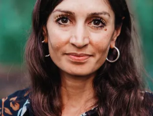 Porträt einer lächelnden Frau mit langen braunen Haaren.