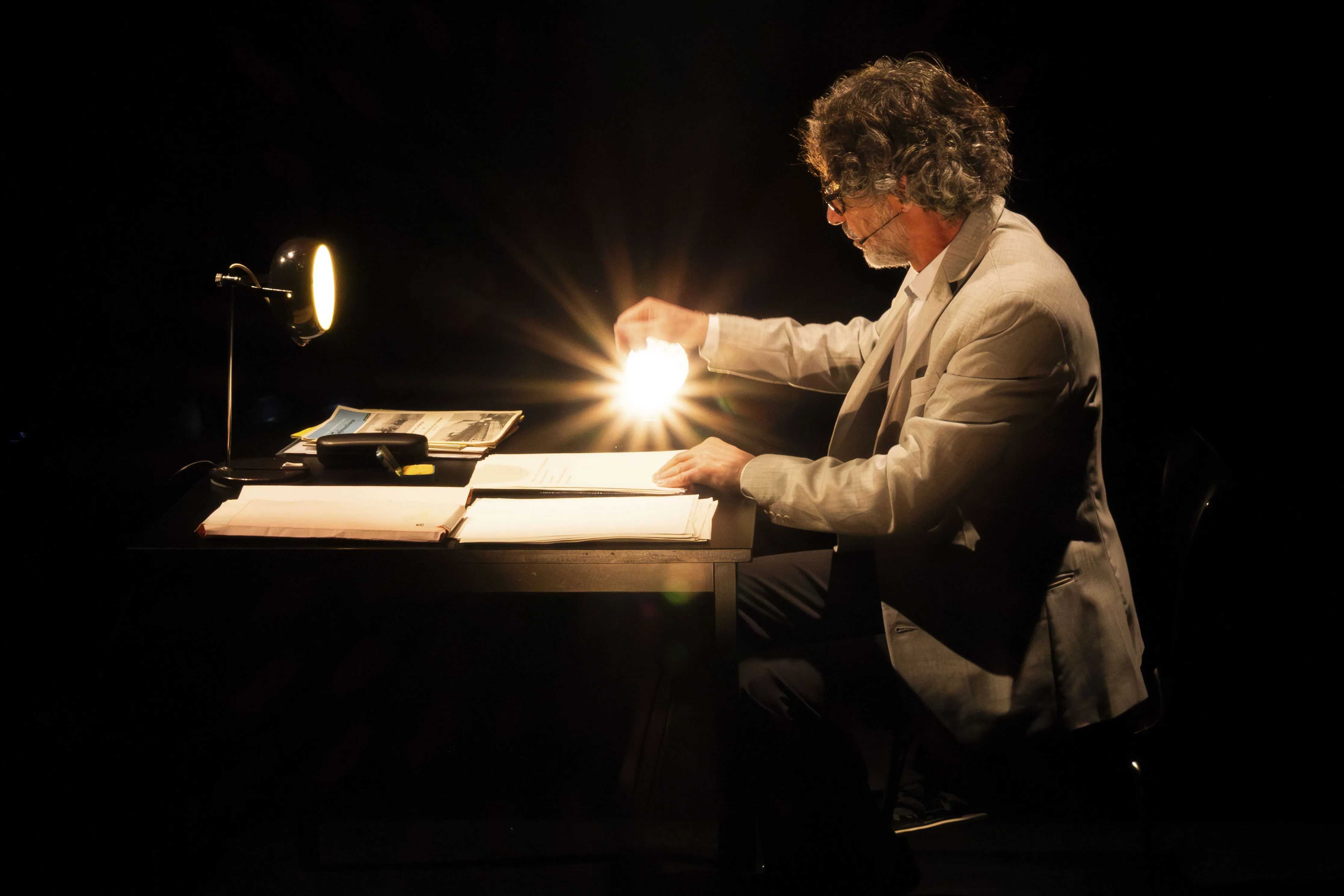 Eine Person sitzt an einem Tisch und leuchtet auf Papierblätter.