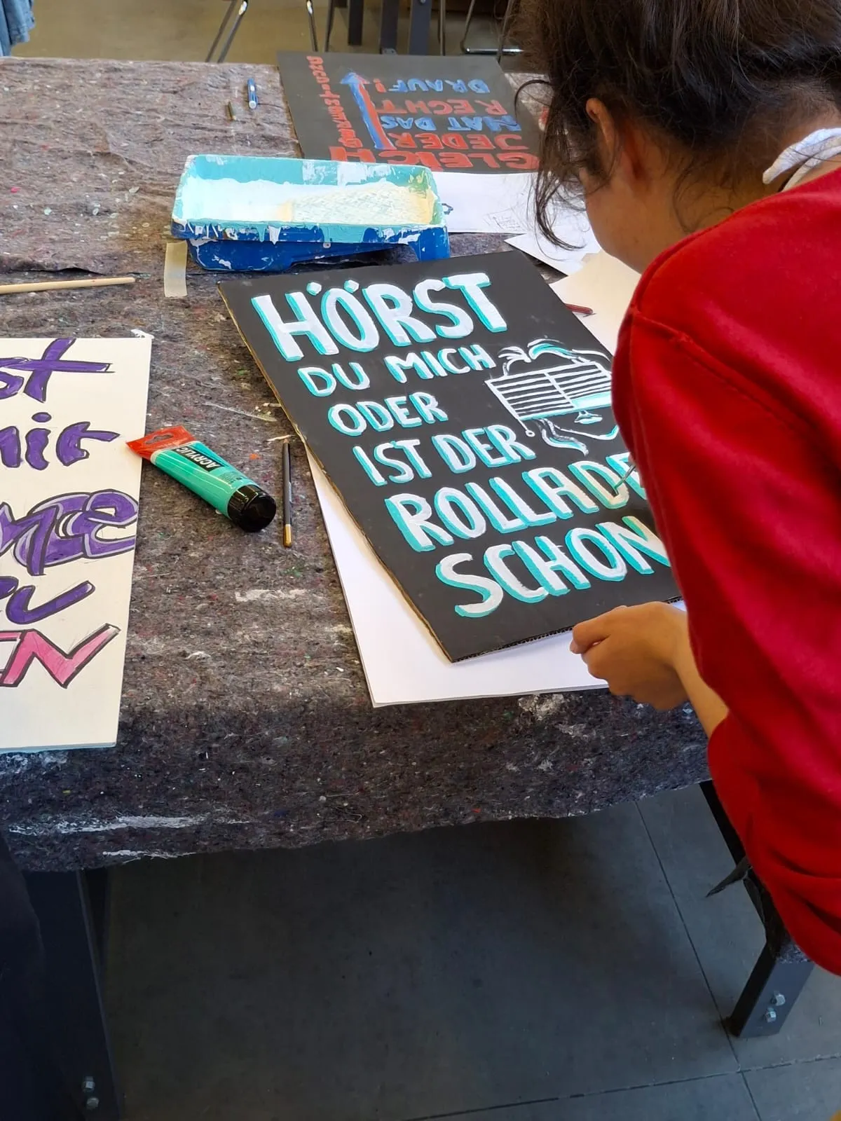 Eine Person, die ein Plakat bemalt.