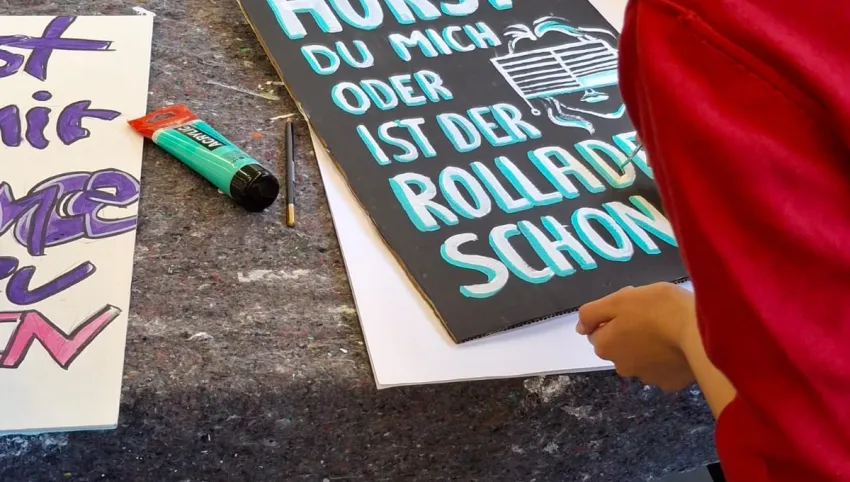 Eine Person, die ein Plakat bemalt.