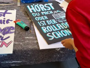 Eine Person, die ein Plakat bemalt.