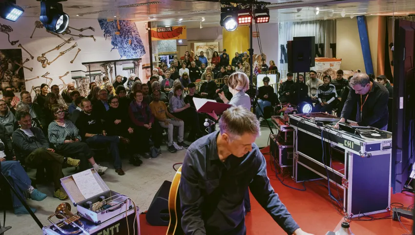 Die Schauspielerin Karla Andrä performt vor Publikum im Festivalzentrum Texte aus dem Gästebuch des Brechthauses mit musikalischer Untermalung von Moritz Illner und Markus Christ