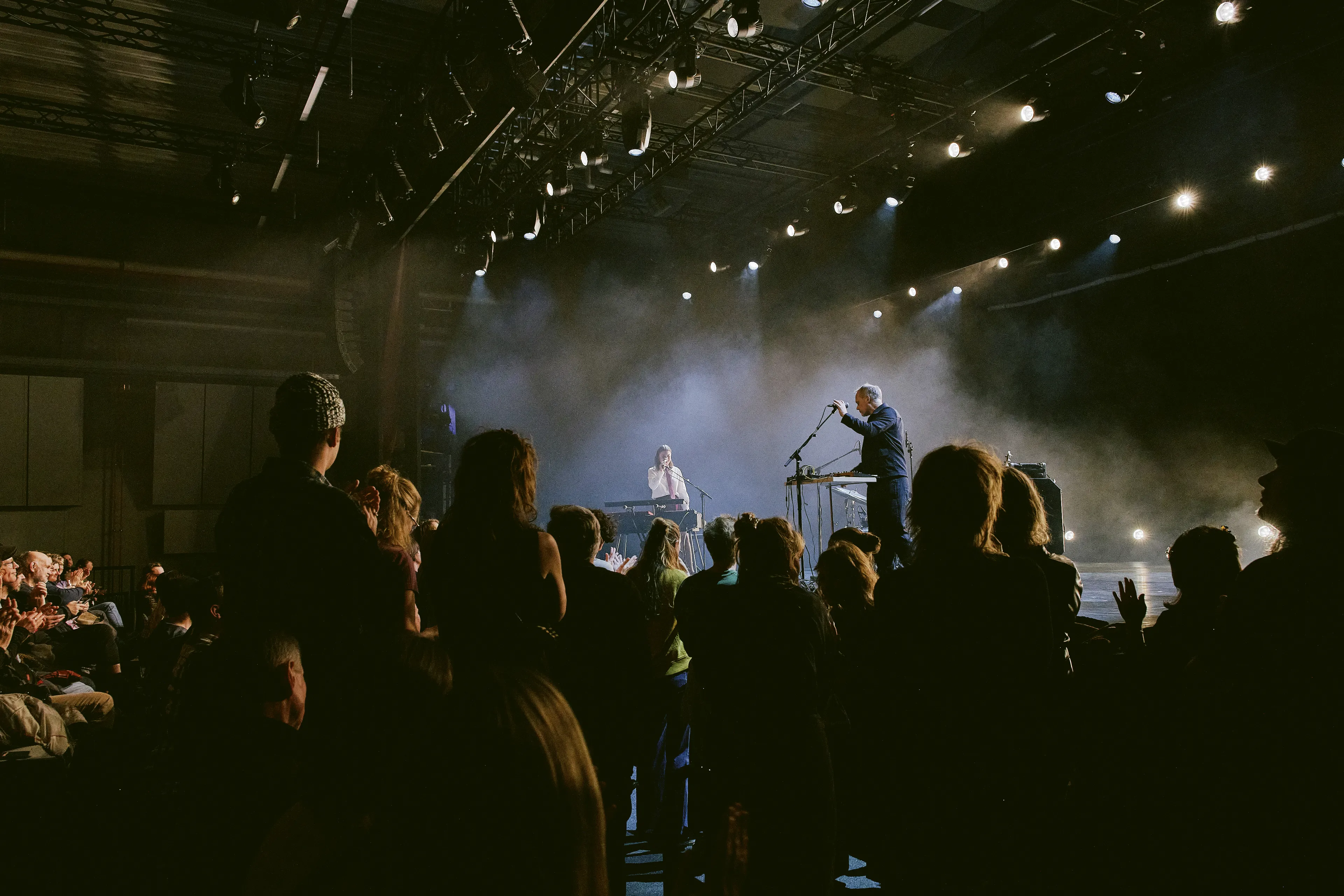 Momentaufnahme des Konzerts mit Sophia Kennedy auf der Bühne im martini-Park. Die Künstlerin steht mit einem Begleitmusiker im Bühnennebel. Davor gebanntes Publikum teils auf den aufsteigenden Rängen sitzend, teils stehend.