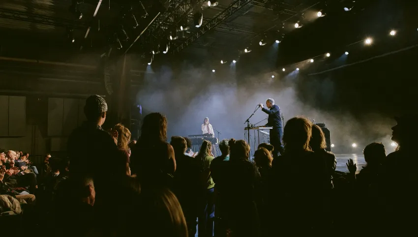Momentaufnahme des Konzerts mit Sophia Kennedy auf der Bühne im martini-Park. Die Künstlerin steht mit einem Begleitmusiker im Bühnennebel. Davor gebanntes Publikum teils auf den aufsteigenden Rängen sitzend, teils stehend.