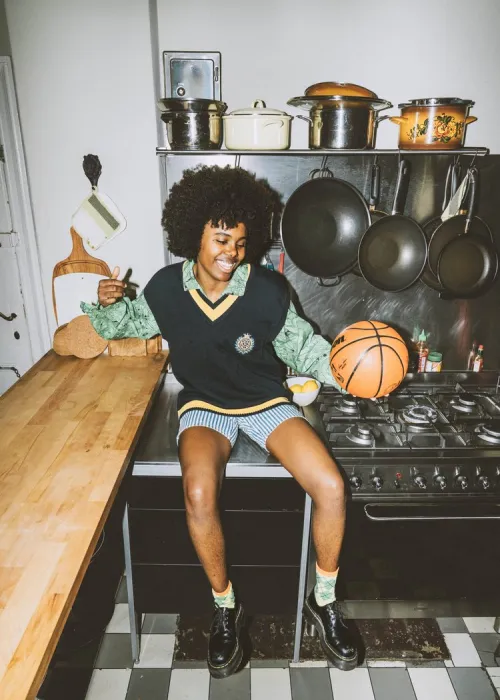 Eine Person sitzt auf einer Küchenplatte und hält einen Basketball in der Hand.