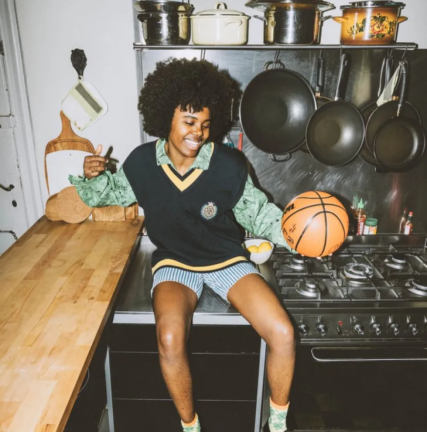 Eine Person sitzt auf einer Küchenplatte und hält einen Basketball in der Hand.