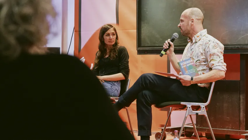 Der Moderator Martin Muth stellt der Autorin Gilda Sahebi im Rahmen der Lesung eine Frage.